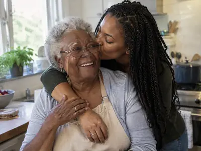 A young woman kisses her grandmother on the cheek in a sunny kitchen